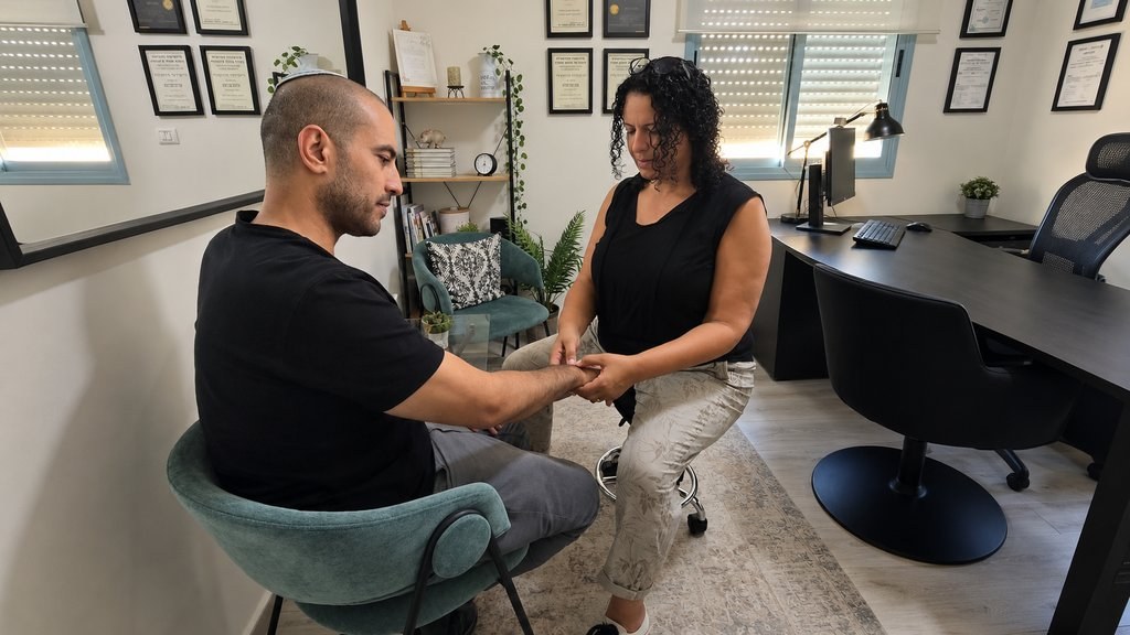 הקליניקה של קרן שירה חייט במושב בקוע — מפגש טיפולי בישיבה, סימון נקודת טיפול בכף היד